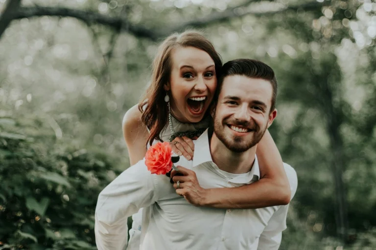 happy groom and bride getting married and the groom is giving the bride a piggyback ride.