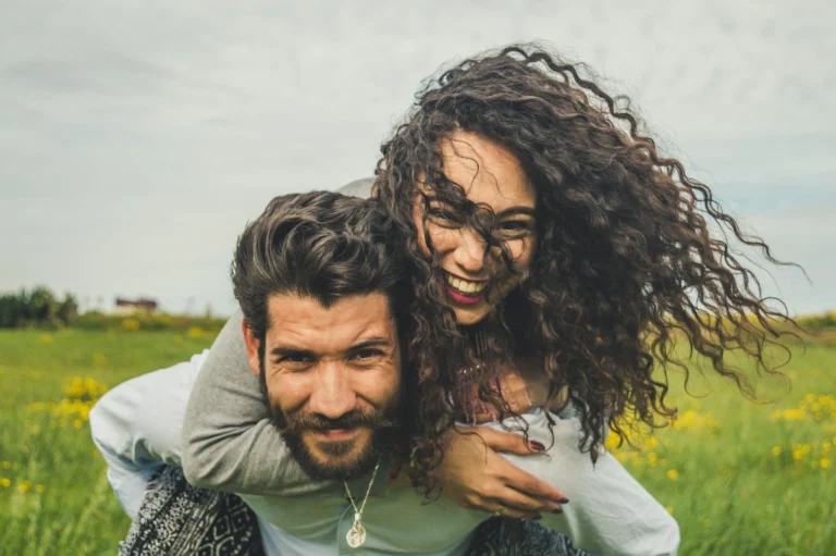 happy couple with groom giving piggyback ride to bride