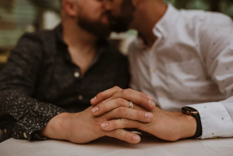 gay couple holding hands while kissing at their wedding